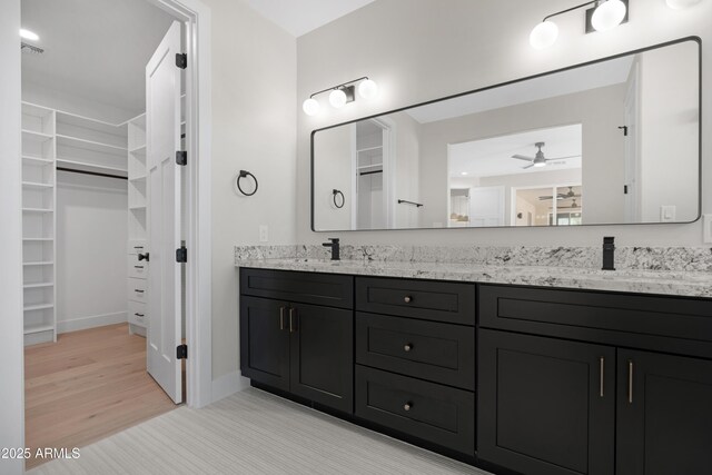 19622 W Pasadena Ave, Litchfield Park, AZ 85340 - full bathroom featuring a walk in closet, a sink, double vanity, a ceiling fan, and baseboards