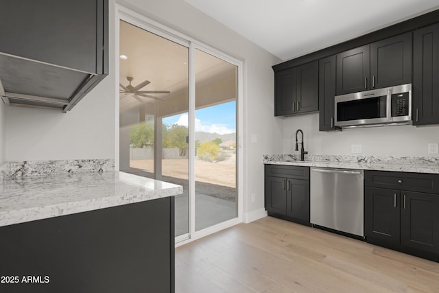 19622 W Pasadena Ave, Litchfield Park, AZ 85340 - kitchen with dark cabinets, light wood-style flooring, ceiling fan, and stainless steel appliances