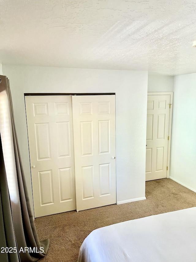 bedroom featuring a closet, baseboards, carpet flooring, and a textured ceiling