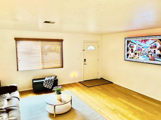 living room with wood finished floors, baseboards, and visible vents