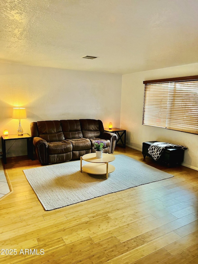 living room with baseboards, wood-type flooring, and visible vents