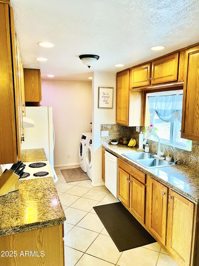 kitchen with a sink, washing machine and clothes dryer, tasteful backsplash, and white appliances