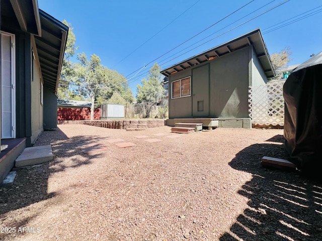 view of yard featuring entry steps, fence, an outdoor structure, and a storage unit