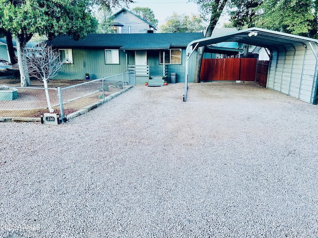 ranch-style house with a carport, fence, a shingled roof, and gravel driveway