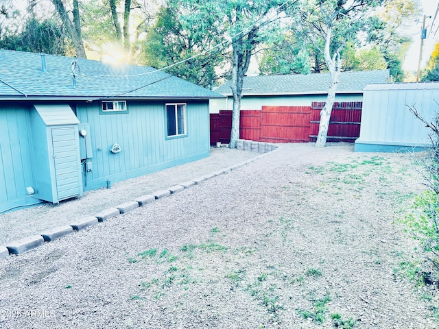 exterior space featuring fence and a shingled roof