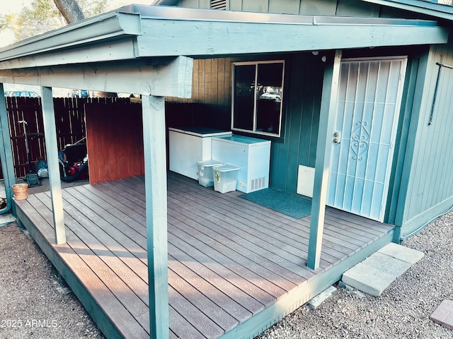 view of side of home with a deck, board and batten siding, and fence
