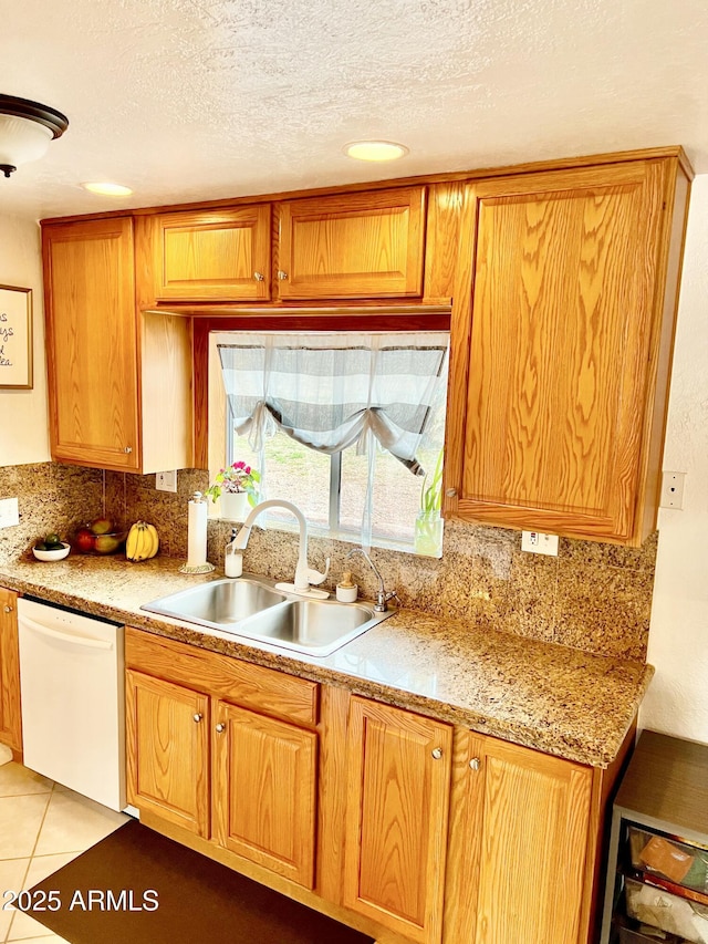 kitchen with tasteful backsplash, light tile patterned flooring, light countertops, dishwasher, and a sink