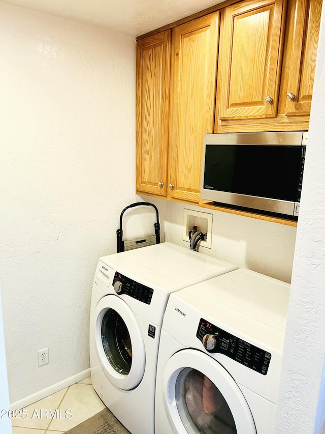 laundry area featuring light tile patterned floors, washer and clothes dryer, baseboards, and cabinet space
