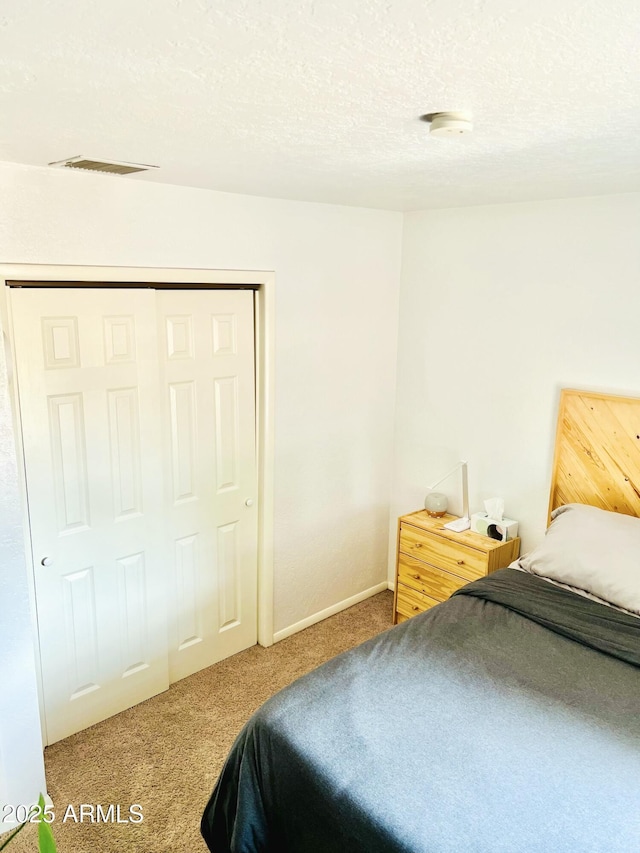carpeted bedroom featuring a textured ceiling, a closet, baseboards, and visible vents
