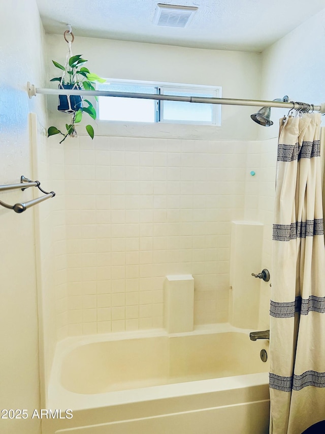 bathroom featuring shower / bathtub combination with curtain and visible vents