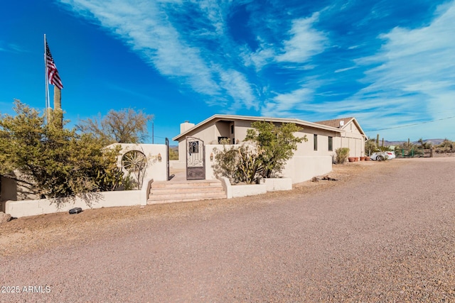 view of front of house with a fenced front yard, a chimney, and stucco siding