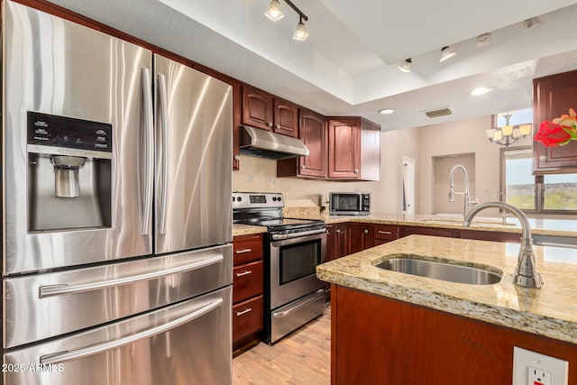 50031 N 27th Ave, New River, AZ 85087 - kitchen with appliances with stainless steel finishes, under cabinet range hood, light wood-type flooring, a sink, and light stone counters