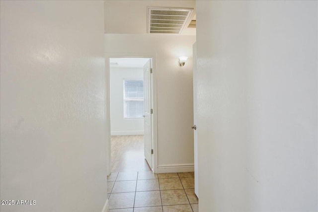 hallway with visible vents, baseboards, and light tile patterned flooring