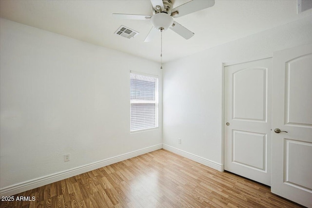 spare room featuring wood finished floors, baseboards, a ceiling fan, and visible vents