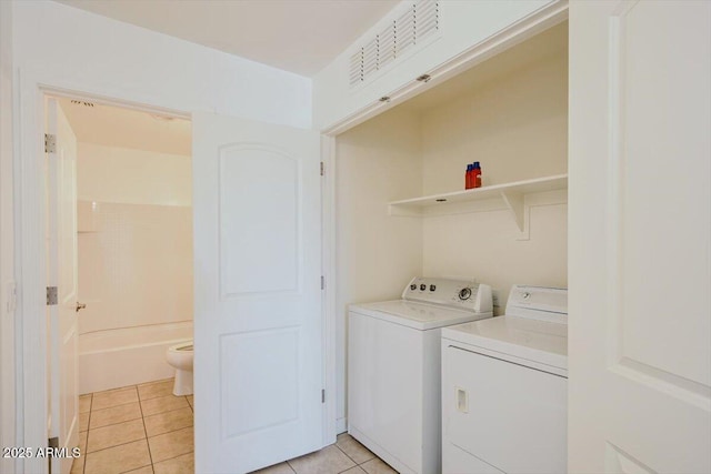 washroom with washer and clothes dryer, light tile patterned floors, and laundry area
