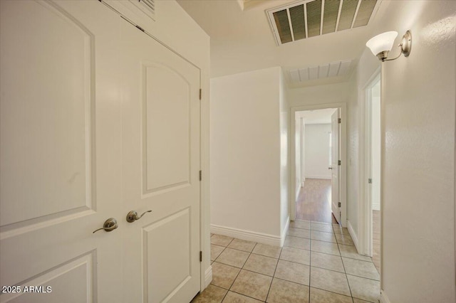 corridor featuring visible vents, baseboards, and light tile patterned floors