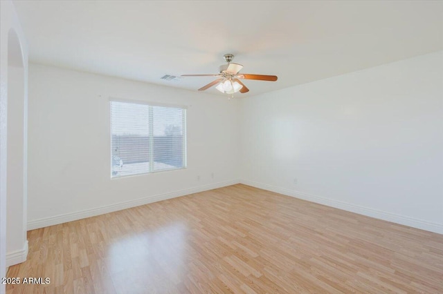 unfurnished room with visible vents, baseboards, arched walkways, a ceiling fan, and light wood finished floors