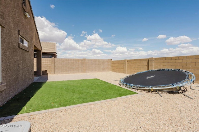 view of yard with a fenced backyard, a trampoline, and a patio