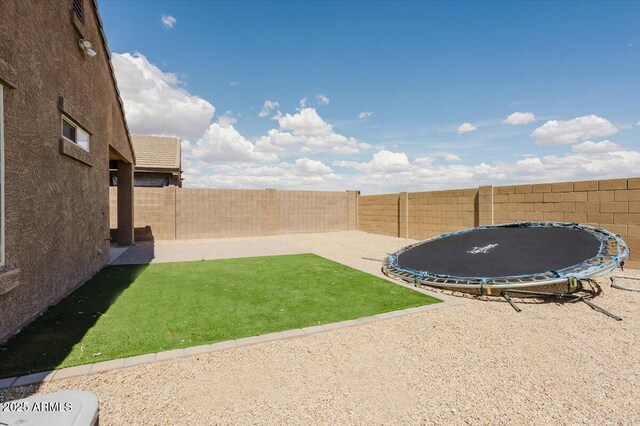 view of yard featuring a patio area, a fenced backyard, and a trampoline