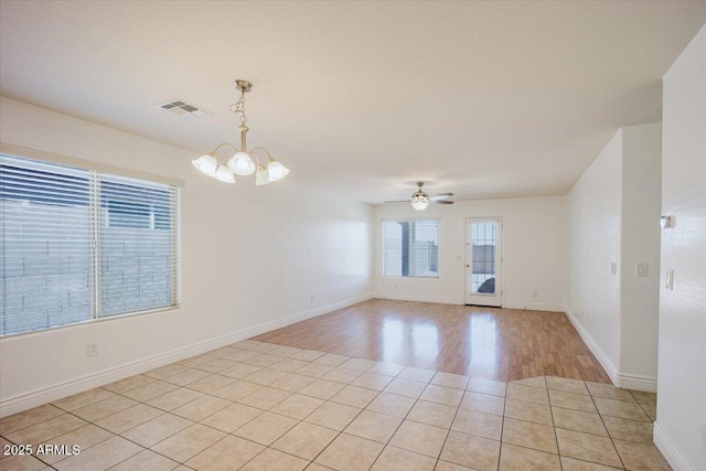 spare room with visible vents, ceiling fan with notable chandelier, baseboards, and light wood-style flooring