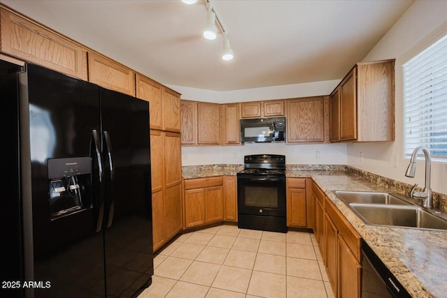 kitchen featuring light tile patterned floors, track lighting, a sink, brown cabinets, and black appliances