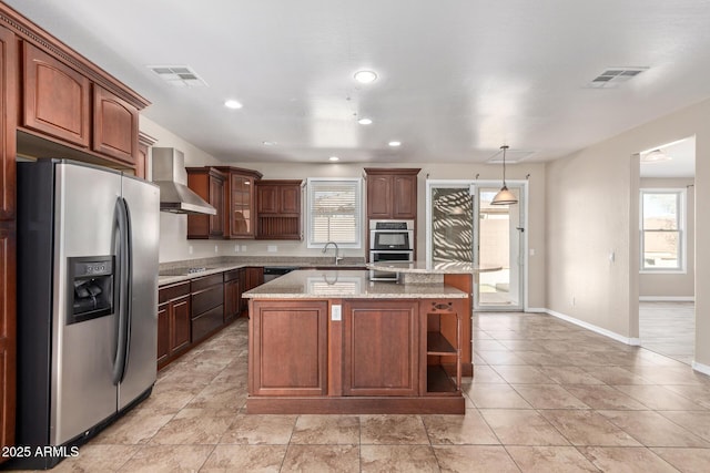 kitchen with visible vents, wall chimney exhaust hood, a kitchen island, hanging light fixtures, and stainless steel appliances