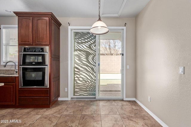 kitchen with a wealth of natural light, double oven, pendant lighting, and a sink