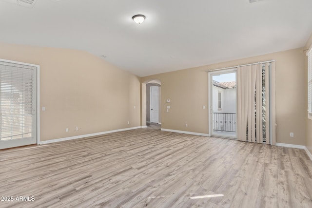 spare room featuring light wood-type flooring, baseboards, and arched walkways