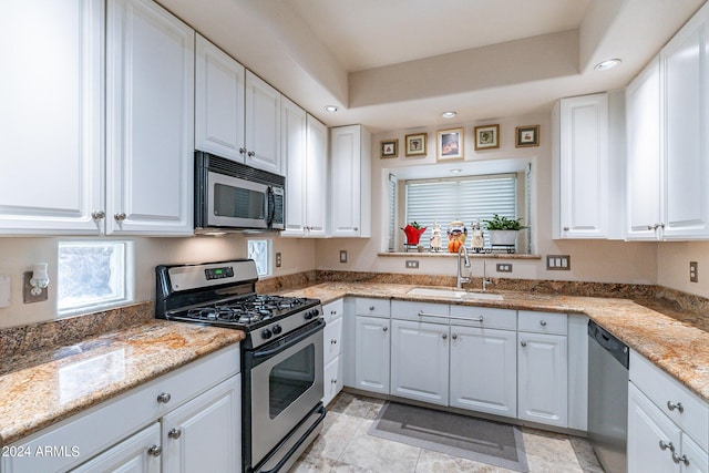 kitchen featuring stainless steel appliances, white cabinetry, light stone countertops, and sink