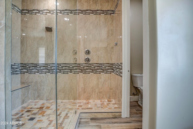 bathroom with toilet, hardwood / wood-style floors, and tiled shower