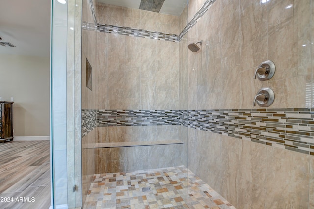 bathroom with tiled shower and hardwood / wood-style floors