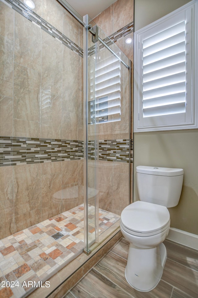 bathroom featuring a shower with shower door and toilet