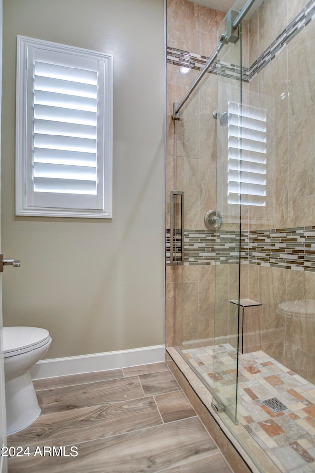 bathroom featuring toilet and a shower with door