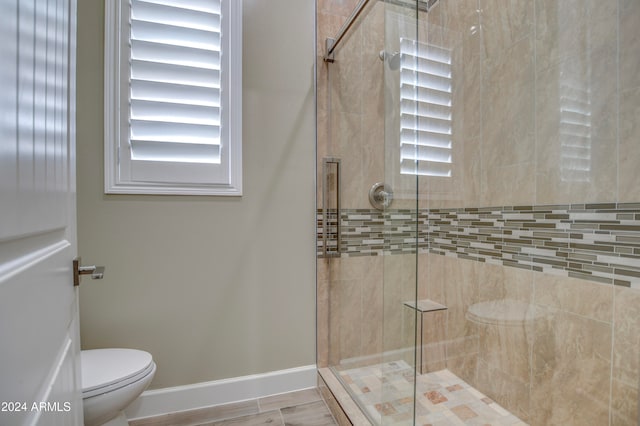 bathroom featuring toilet and a shower with shower door