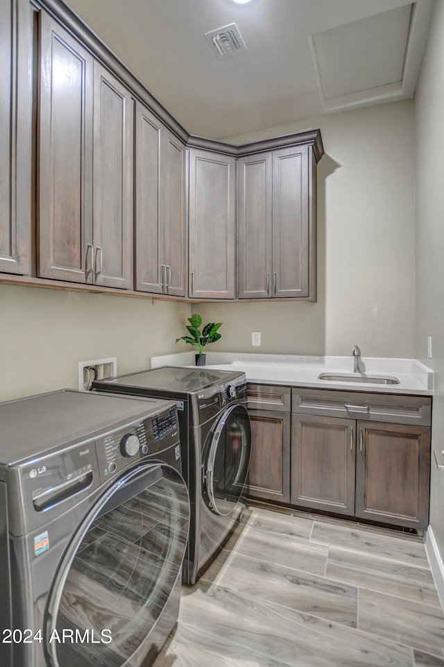 washroom featuring cabinets, sink, washer and clothes dryer, and light hardwood / wood-style floors