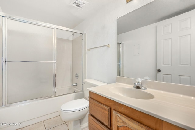 full bath with bath / shower combo with glass door, toilet, visible vents, tile patterned flooring, and vanity