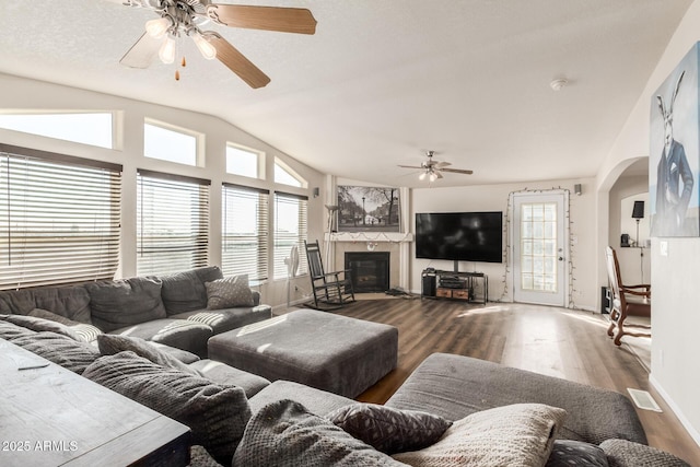 living room with hardwood / wood-style flooring, ceiling fan, vaulted ceiling, and a textured ceiling