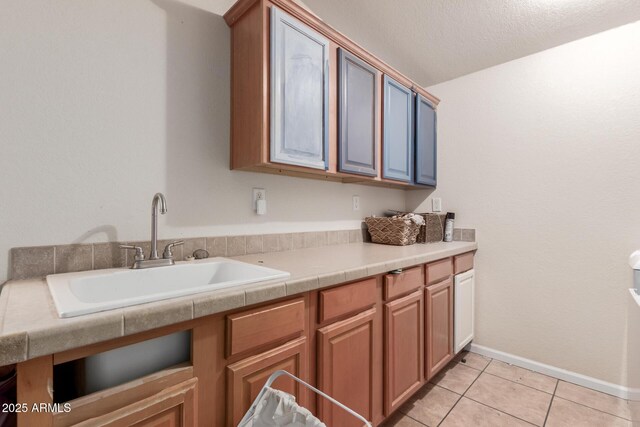 kitchen featuring sink, a textured ceiling, and light tile patterned floors