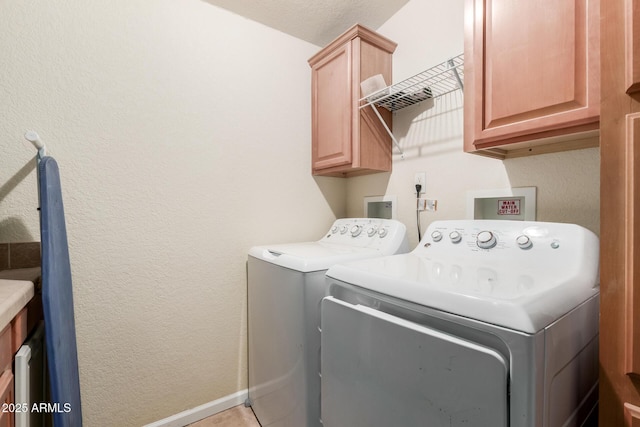 laundry room featuring cabinets, light tile patterned floors, and independent washer and dryer