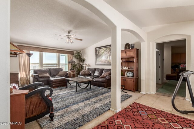 living room featuring ceiling fan, light tile patterned floors, and vaulted ceiling