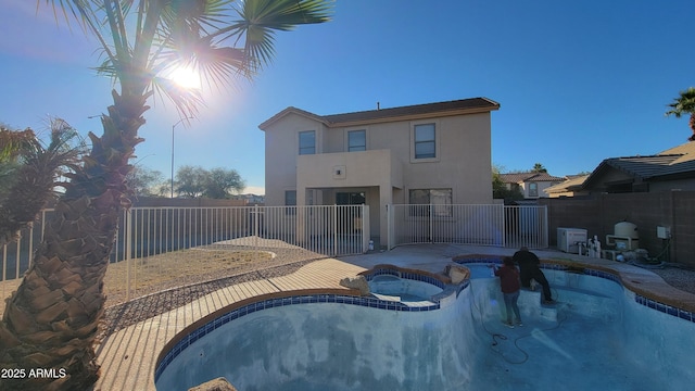 rear view of property with a pool with hot tub