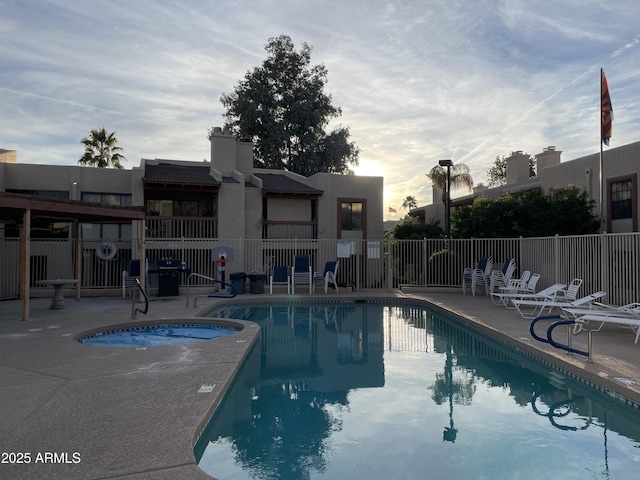 pool at dusk with a community hot tub and a patio area