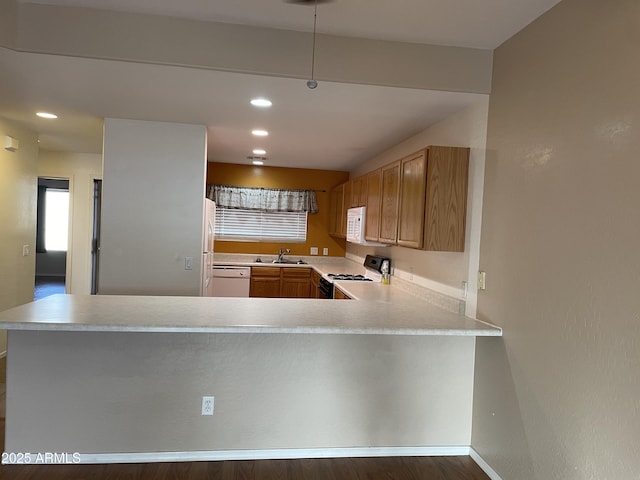 kitchen with white appliances, dark hardwood / wood-style flooring, kitchen peninsula, and sink