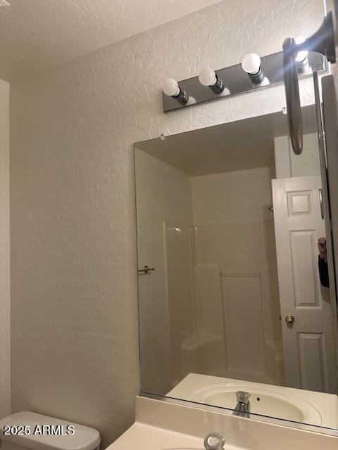 bathroom featuring walk in shower, vanity, and toilet