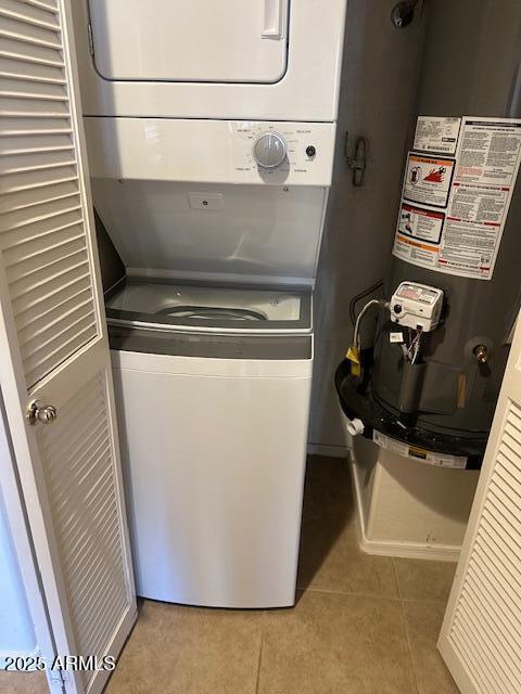 clothes washing area featuring gas water heater, stacked washer and clothes dryer, and light tile patterned floors