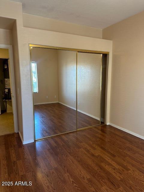 unfurnished bedroom with a closet and dark hardwood / wood-style floors