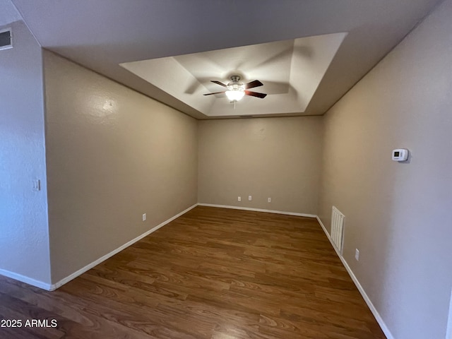 spare room featuring ceiling fan, dark hardwood / wood-style flooring, and a raised ceiling