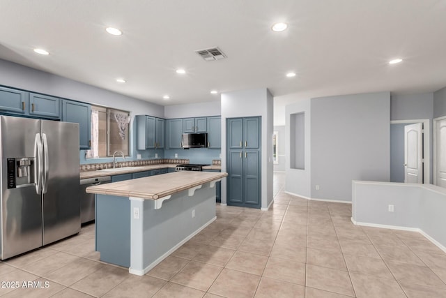 9142 W Pontiac Dr, Peoria, AZ 85382 - kitchen featuring stainless steel appliances, blue cabinets, a kitchen island, light tile patterned floors, and recessed lighting