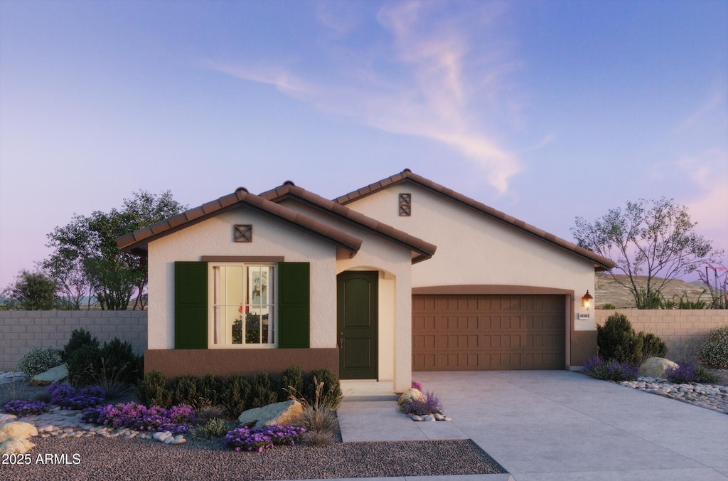 mediterranean / spanish-style home with stucco siding, fence, concrete driveway, an attached garage, and a tiled roof