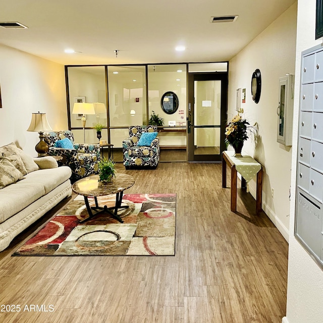 living area featuring visible vents, baseboards, and wood finished floors